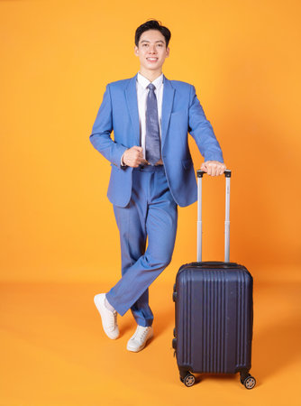 Image of young Asian business man holding suitcase on backgroundの写真素材