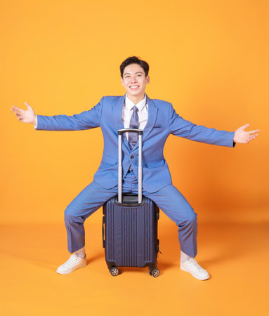 Image of young Asian business man holding suitcase on backgroundの写真素材