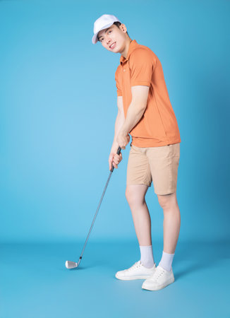 Image of young Asian man golfer on blue backgroundの写真素材