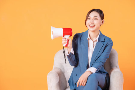 Photo of young Asian businesswoman holding megaphone on backgroundの写真素材