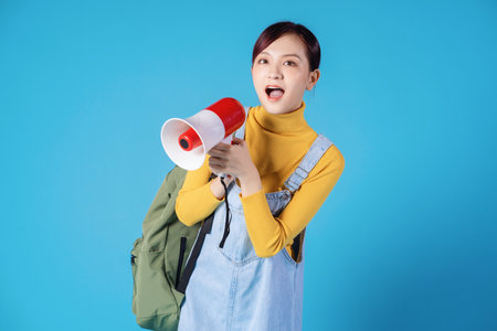 Young Asian student posing on blue backgroundの写真素材