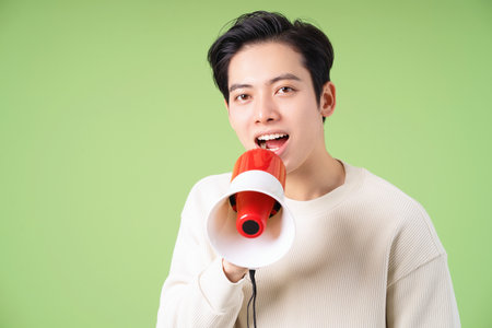 Image of young Asian man holding speaker on backgroundの写真素材
