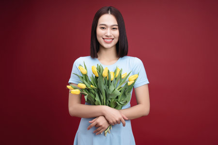 Image of young Asian woman holding tulips flowers on backgroundの写真素材