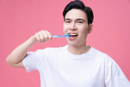 Young Asian man holding toothbrush on backgroundの写真素材