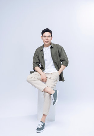 Young Asian man sitting on backgroundの写真素材