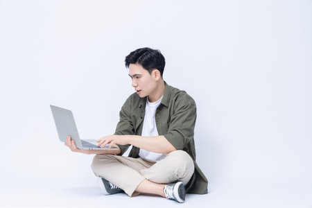 Young Asian business man sitting and using laptop on backgroundの写真素材