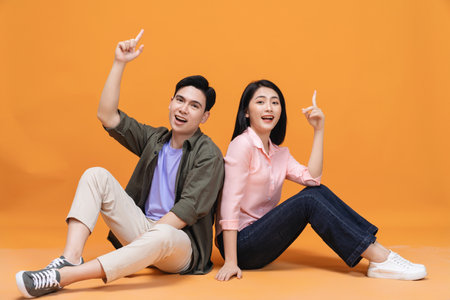 Young Asian couple sitting on backgroundの写真素材