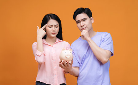 Young Asian couple holding piggy bank on backgroundの写真素材