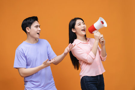 Young Asian couple with megaphone on backgroundの写真素材