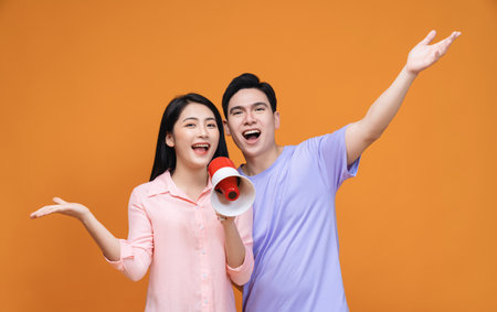 Young Asian couple with megaphone on backgroundの写真素材