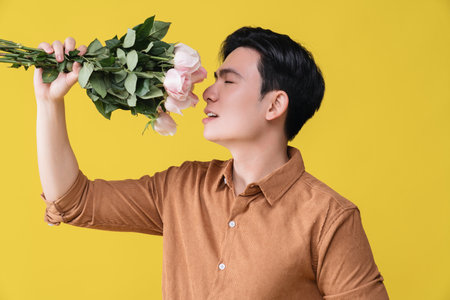 Young Asian man holding flower on backgroundの写真素材