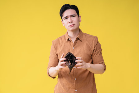 Young Asian man with empty wallet on background