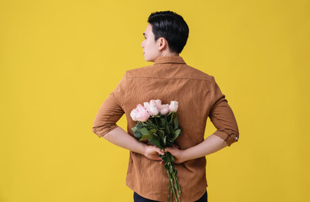 Young Asian man holding flower on backgroundの写真素材