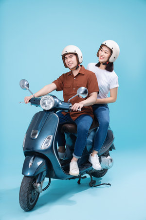 Young Asian couple ride scooter on backgroundの写真素材