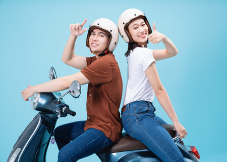 Young Asian couple ride scooter on background
