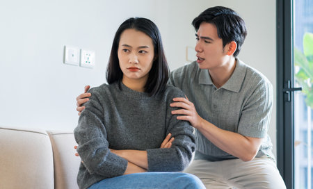 Two young adults engage in a serious conversation in a stylish apartment. The woman appears upset while the man tries to communicate and resolve their differences in a cozy setting.の写真素材