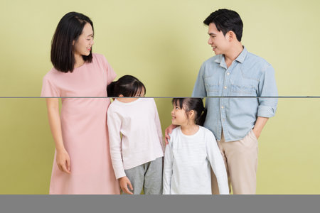 A family of four shares joyful moments in a cozy indoor setting. The parents and their two daughters engage in laughter and conversation, creating a warm atmosphere.の写真素材
