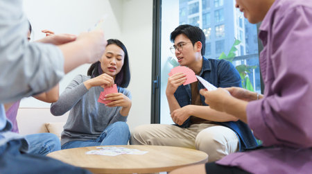 A group of friends engages in a lively card game inside a stylish apartment. Laughter and friendly...