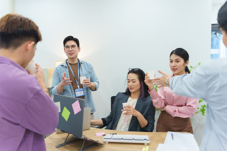 A group of diverse professionals engages in a collaborative discussion at a stylish office. They...