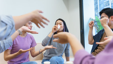 A group of friends socialize in a stylish indoor space, sharing drinks and animated gestures. Laughter fills the air as they engage in conversation, enjoying each other's company.の写真素材