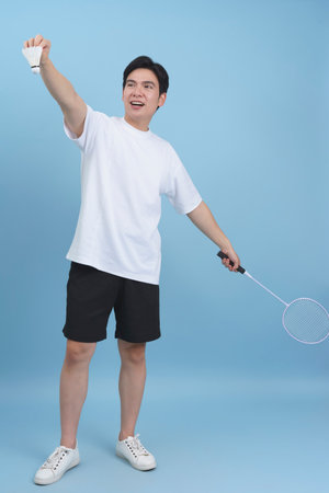 A young male displays excitement while holding a shuttlecock and badminton racket.の写真素材