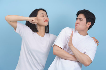 Two individuals are playfully pretending to argue, with one throwing a playful punch while the other...