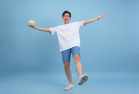 A young man dressed in a white shirt and denim shorts smiles while striking a playful pose.の写真素材
