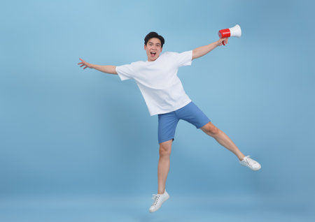 A young man exudes enthusiasm while jumping in mid-air, holding a megaphone in one hand. He wears...