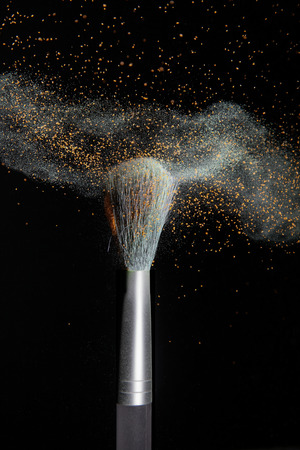 makeup brushes and powder in a balck background