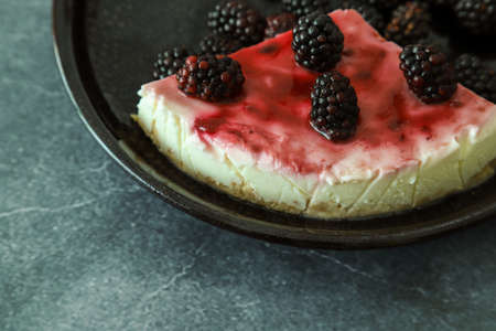 a piece of cheesecake with blackberry on the black dishの写真素材