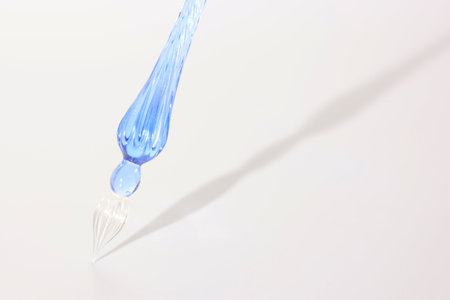 a glass pen and its shadow in a white backgroundの写真素材