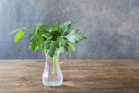Italian parsley in the glass bottle on the wooden table.の写真素材