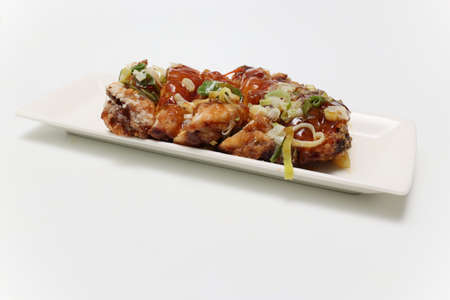 Deep-fried chicken with soy sauce on the white plate isolated on a white background.