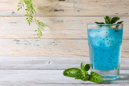 Basil seeds in the light blue drink on the wooden table.の写真素材