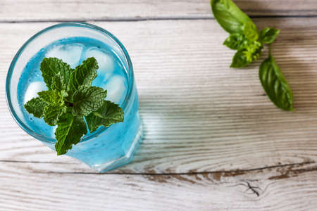 Basil seeds in the light blue drink on the wooden table.の写真素材