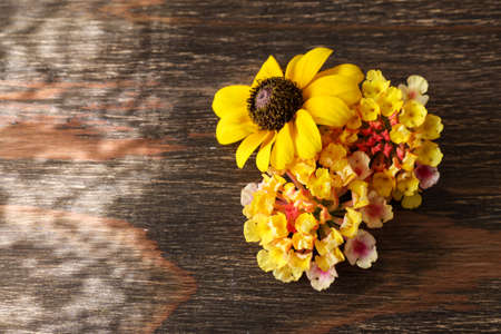 Flower head of Lantana and Black-eyed Susan on the wooden table.