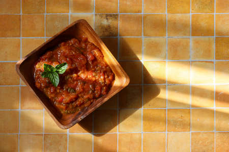 Tomatoes sauce in the wooden bowl isolated on a tile pattern background.の写真素材