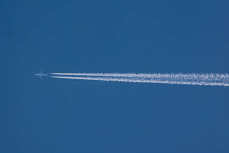 A jet airliner and its contrail in the blue sky.の写真素材