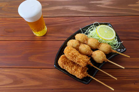 Deep-fried skewered onion ,pork and quail eggs on the black crockery on the wooden table.の写真素材