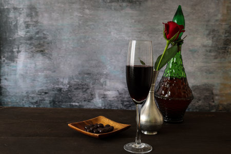 Red wine in the green bottle on the wooden table.