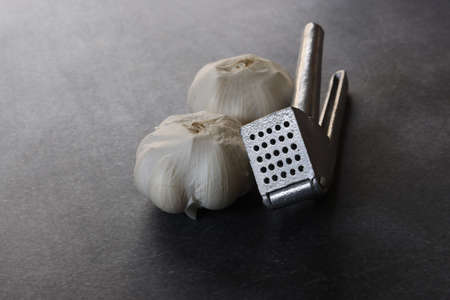 Garlic and garlic press isolated on a concrete pattern background.の写真素材