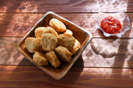 chicken nuggets in a wooden bowl on a wooden table.