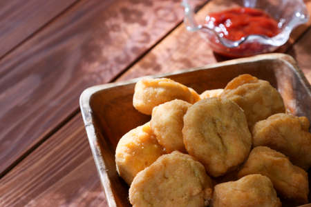 chicken nuggets in a wooden bowl on a wooden table.の写真素材