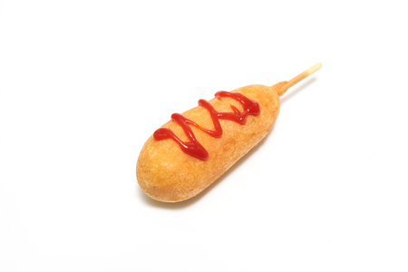 Corn dog with ketchup isolated on a white background.の写真素材