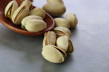 Pistachios on a wooden spoon isolated on a marble pattern background.