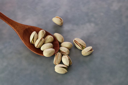 Pistachios on a wooden spoon isolated on a marble pattern background.
