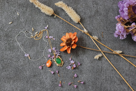 Necklace and dried flower on a stone pattern board.の写真素材