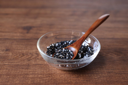 Black sesame and salt in a glass tableware on a wooden table.の写真素材