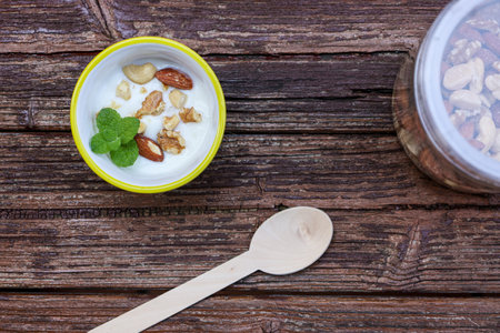 Yogurt with nuts on the wooden table.