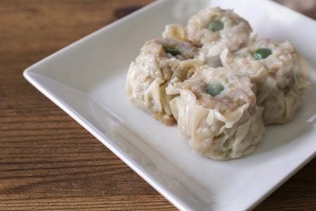 Chinese steamed dumplings on a plate on a wooden tableの写真素材